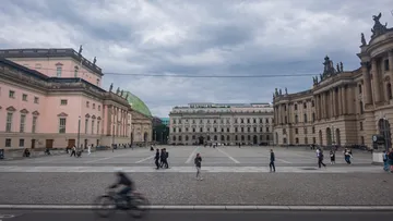 Radfahrer fährt durch historischen Stadtplatz.