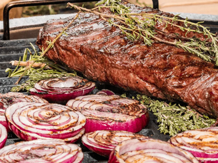 Grilled steak with onions and herbs on the grill.