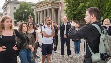Tour guide speaking to group outside building.