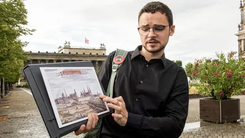 Mann zeigt einen historischen Druck draußen.