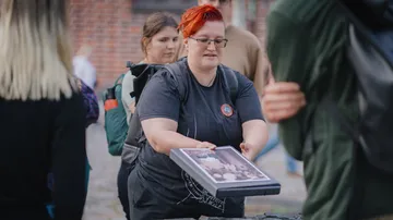 Person hält gerahmtes Foto, Außentreffen.