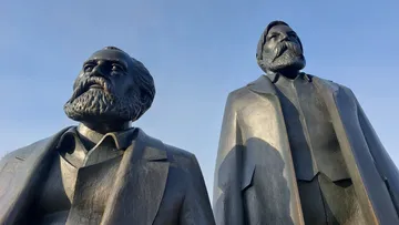Zwei Statuen vor blauem Himmel stehend.