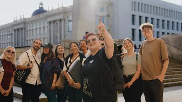 Group taking selfie outside large building.