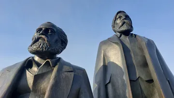 Zwei Statuen stehen vor klarem Himmel.