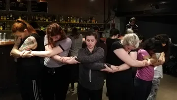 Personen umarmen sich in einer Bar.