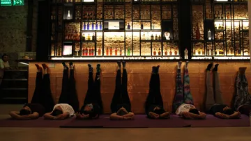 Menschen machen Yoga, Beine an Bar hoch.