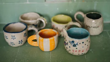 Ceramic mugs displayed on a green surface.