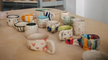 Bunte handgemachte Tassen auf Holztisch.