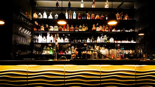 Illuminated bar with bottles and glasses.