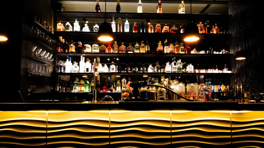 Beleuchtete Bar mit Flaschen und Gläsern.
