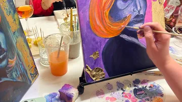 Person painting abstract face on canvas.