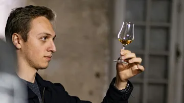 Person begutachtet Glas mit Flüssigkeit drinnen.