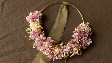 Kranz mit lila Blumen auf Stoffhintergrund.