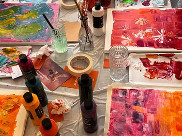 Colorful paintings and art supplies on table.