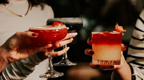 Three cocktails held by people indoors.