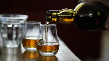 Whiskey poured into glasses on table.