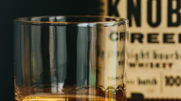 Glas mit Whiskey vor Flasche.