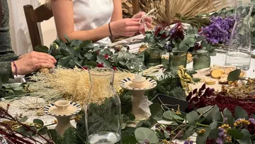 Menschen gestalten Blumenarrangements am Tisch.
