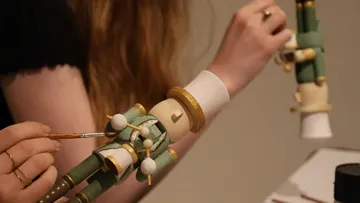 Hands painting green wooden toy soldier.