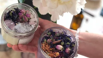 Hände halten Gläser mit getrockneten Blumen.