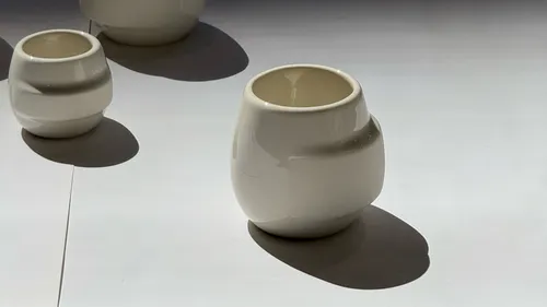 White ceramic vases casting shadows on table.