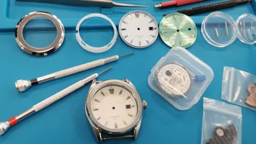Watch parts on blue workspace mat.