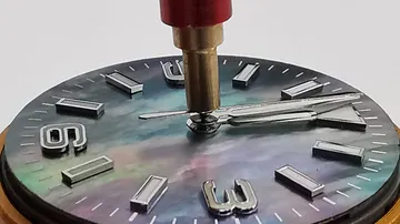 Watch face being adjusted with tool.