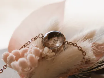 A round ring lies between delicate flowers and feathers.