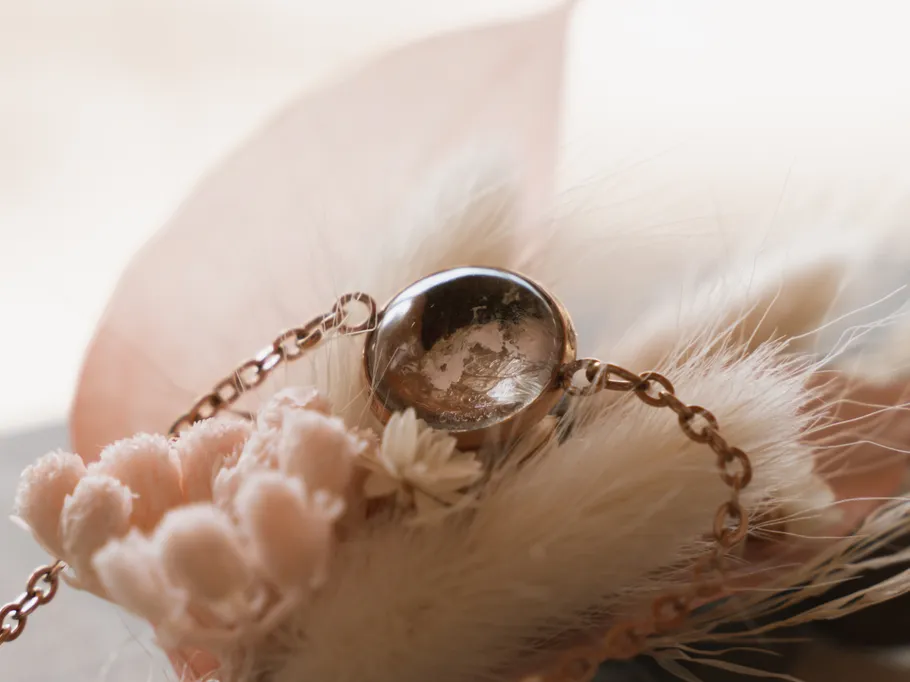 Ein runder Ring liegt zwischen zarten Blumen und Federn.