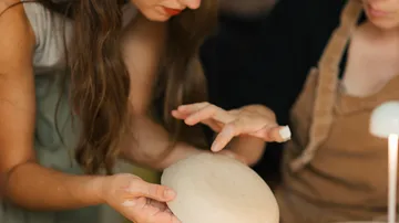 Hands shaping clay on a pottery wheel.