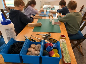 Children crafting at wooden table workshop.