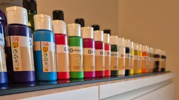 Acrylfarben-Flaschen auf einem Regal aufgereiht.