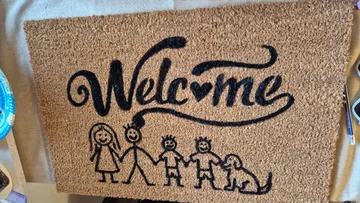 Fußmatte mit "Welcome" und Familienzeichnung.