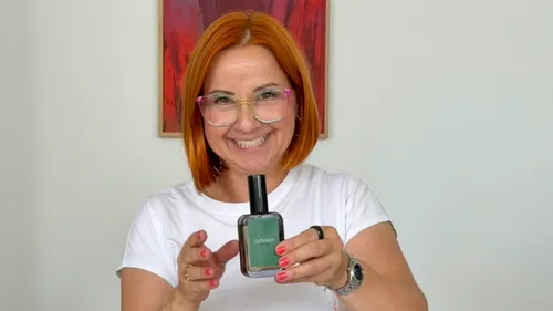 Frau hält Parfümflasche, lächelnd drinnen.