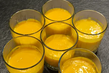 Sieben Gläser mit orangefarbener Flüssigkeit.
