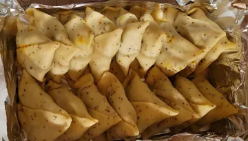 Samosas arranged in foil-lined tray.