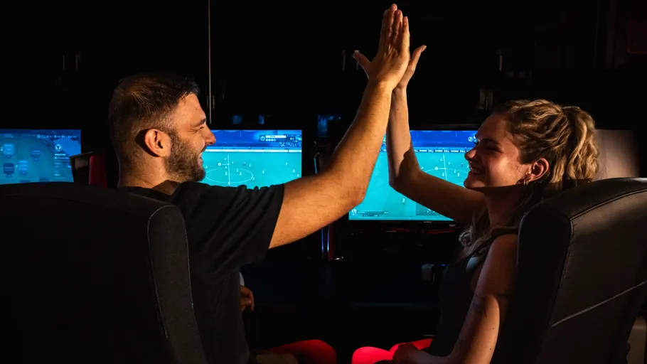 Zwei Spieler geben sich in dunklem Raum einen High-Five.