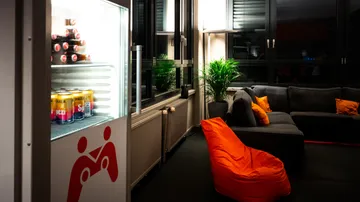 Kühlschrank mit Cola neben gemütlichen Sofas.