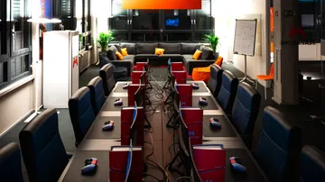 Office with gaming setup on tables.