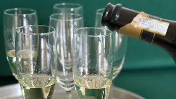 Champagner in Glas auf Tablett gegossen.