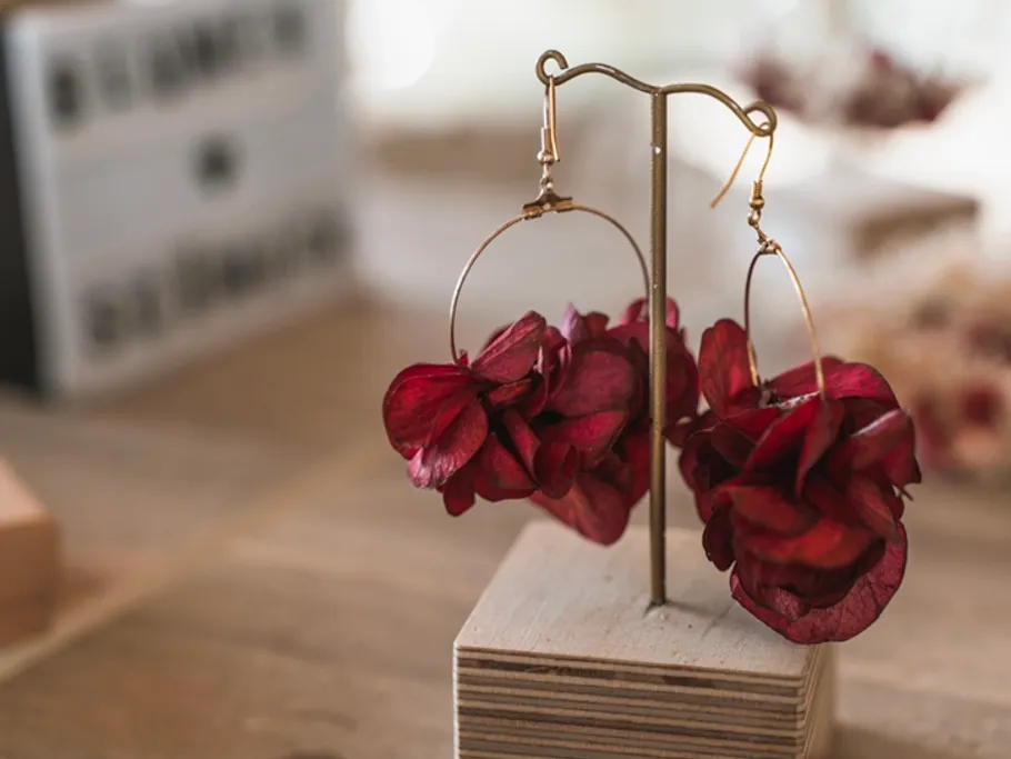 Red earrings hang from a stand on a table.