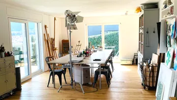 Kunststudio mit Tisch und Staffeleien.