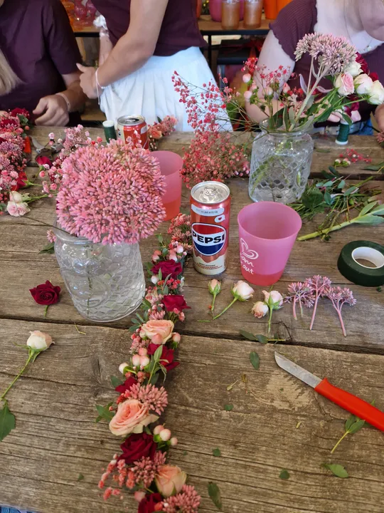 Flowers arranged on table with people crafting.