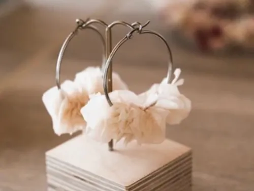 Two earrings hang decoratively on a stand.