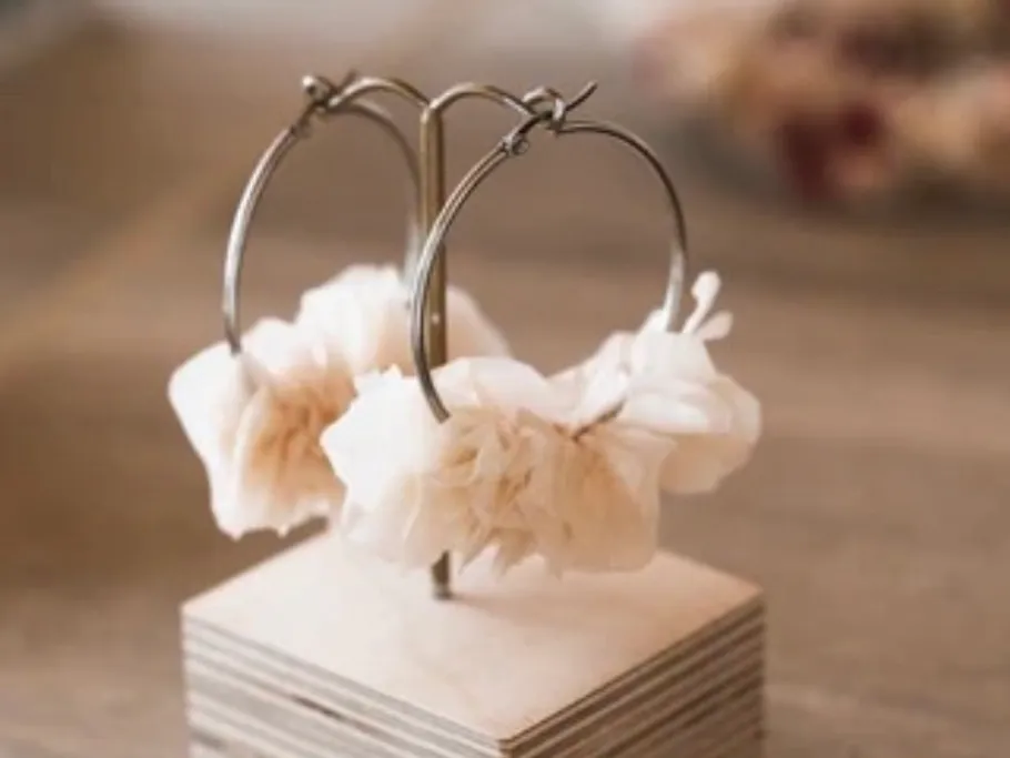 Two earrings hang decoratively on a stand.