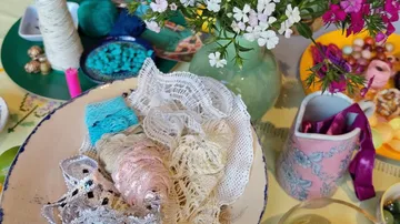 Lace and flowers arranged with crafting supplies.