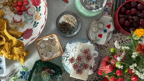 Bastelmaterialien und Kirschen auf buntem Tisch.