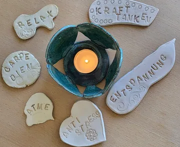 Candle in holder surrounded by clay words.