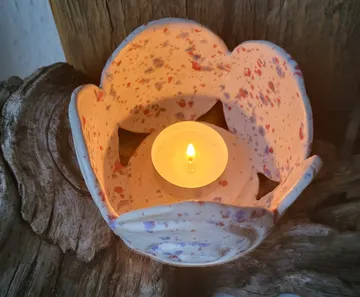 Candle lit in a ceramic holder on wood.