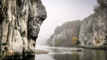 Boat navigating between tall rocky cliffs.